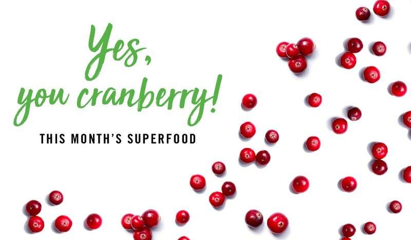 Scattered fresh cranberries with text "Yes, you cranberry! This month's superfood" on white background.